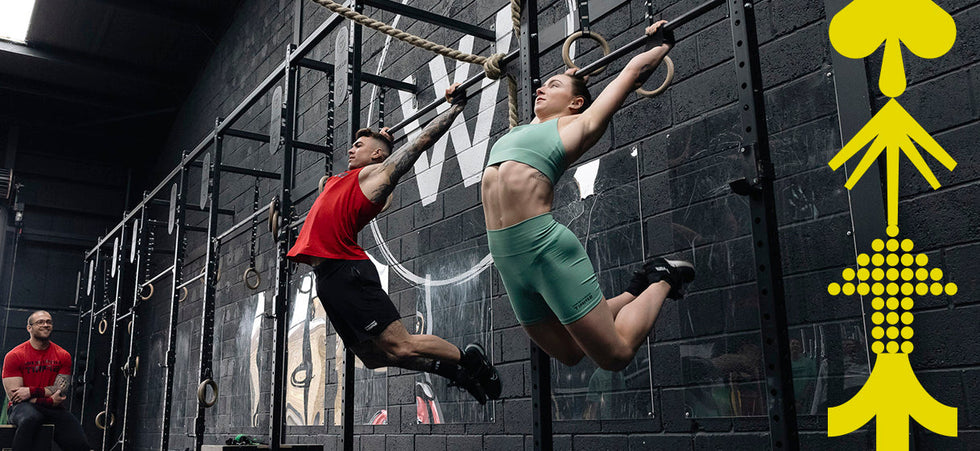 Athletes performing kipping pull-ups on gymnastic rings wearing Northern Spirit training apparel in a CrossFit® box — strength and coordination in motion.