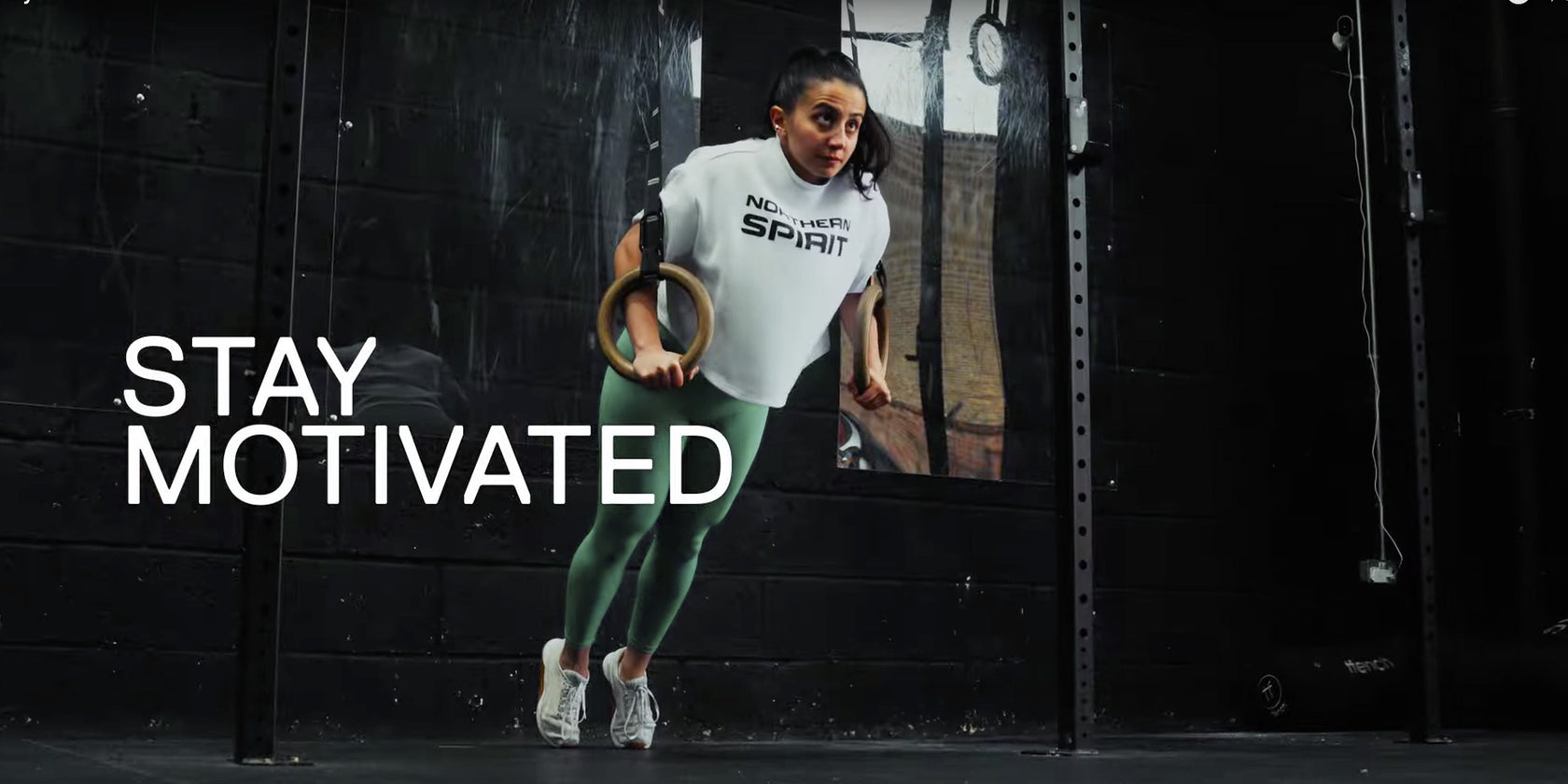 Person exercising with rings in a gym setting, with 'Stay Motivated' text.