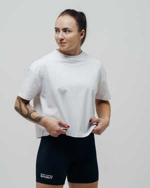 Woman wearing a white t-shirt and black shorts with visible branding on a plain background
