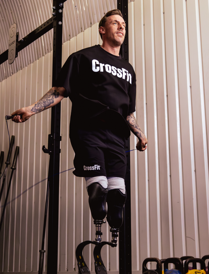 Person wearing a CrossFit t-shirt and shorts in a gym setting.