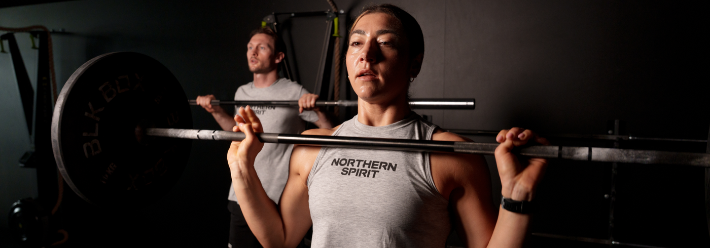 Female and male athletes lifting barbells wearing Northern Spirit training apparel – performance-focused CrossFit clothing for strength and endurance.