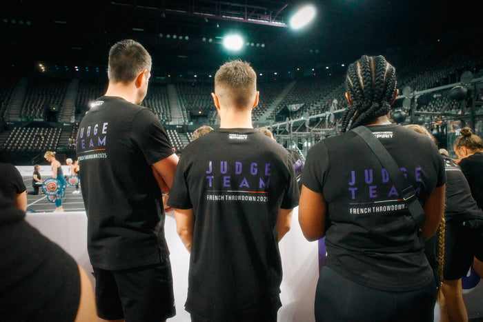 Judges wearing Northern Spirit shirts during the French Throwdown 2025, overseeing CrossFit® athletes on the competition floor in a packed arena.